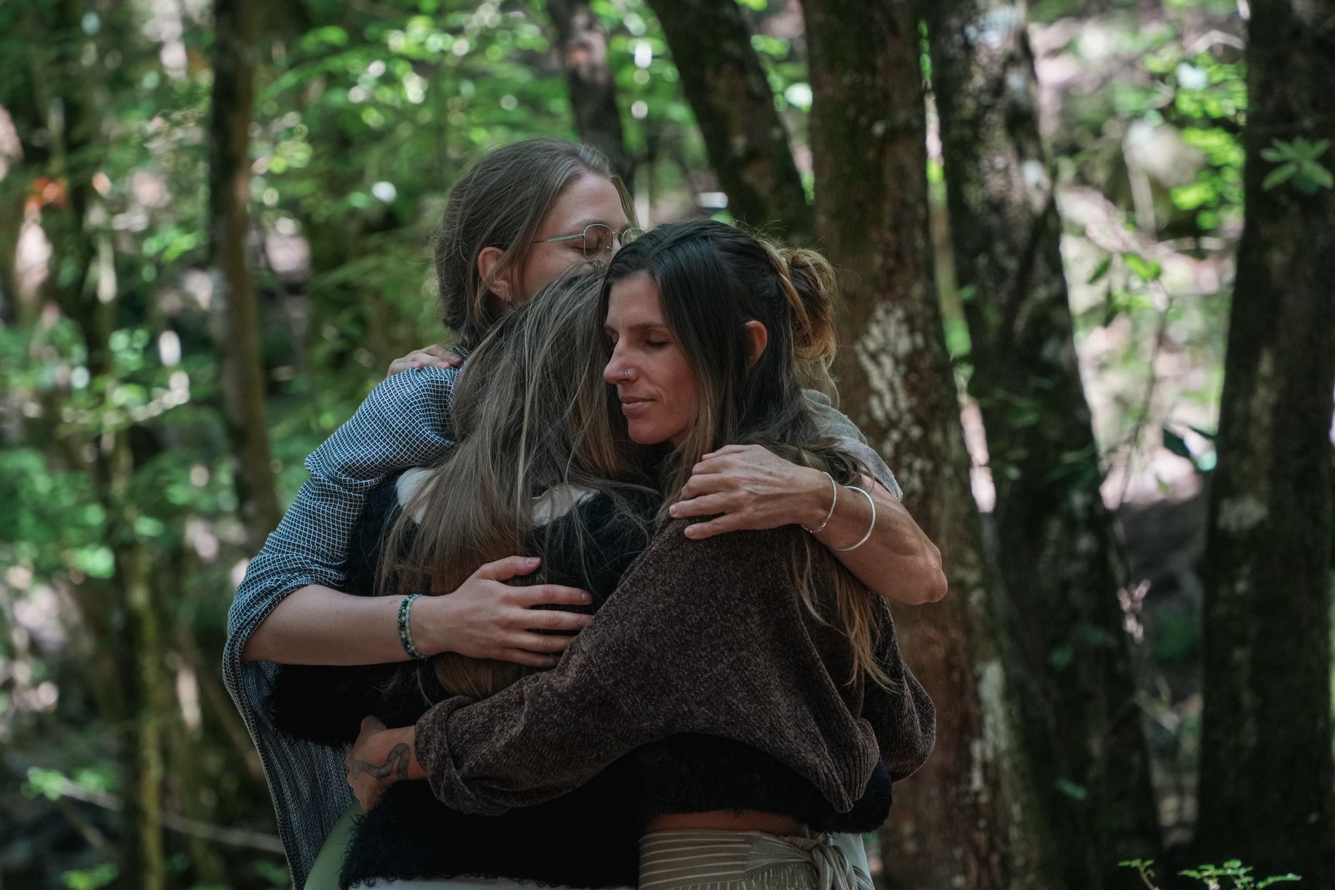 Madison in a close hug with two other people among trees