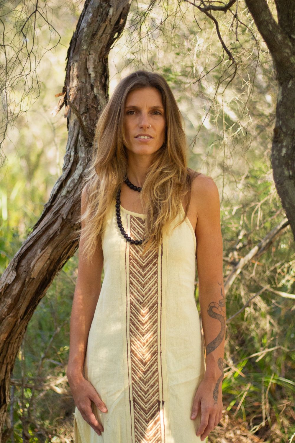 Madison Louise standing between two trees in soft sunlight